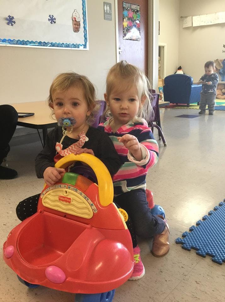 Two children playing with a red toy car