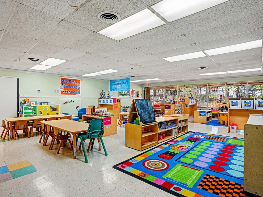 Empty classroom with small tables, chairs, and a colorful rug
