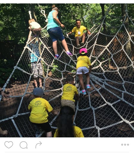 People and children climbing on a large rope net structure