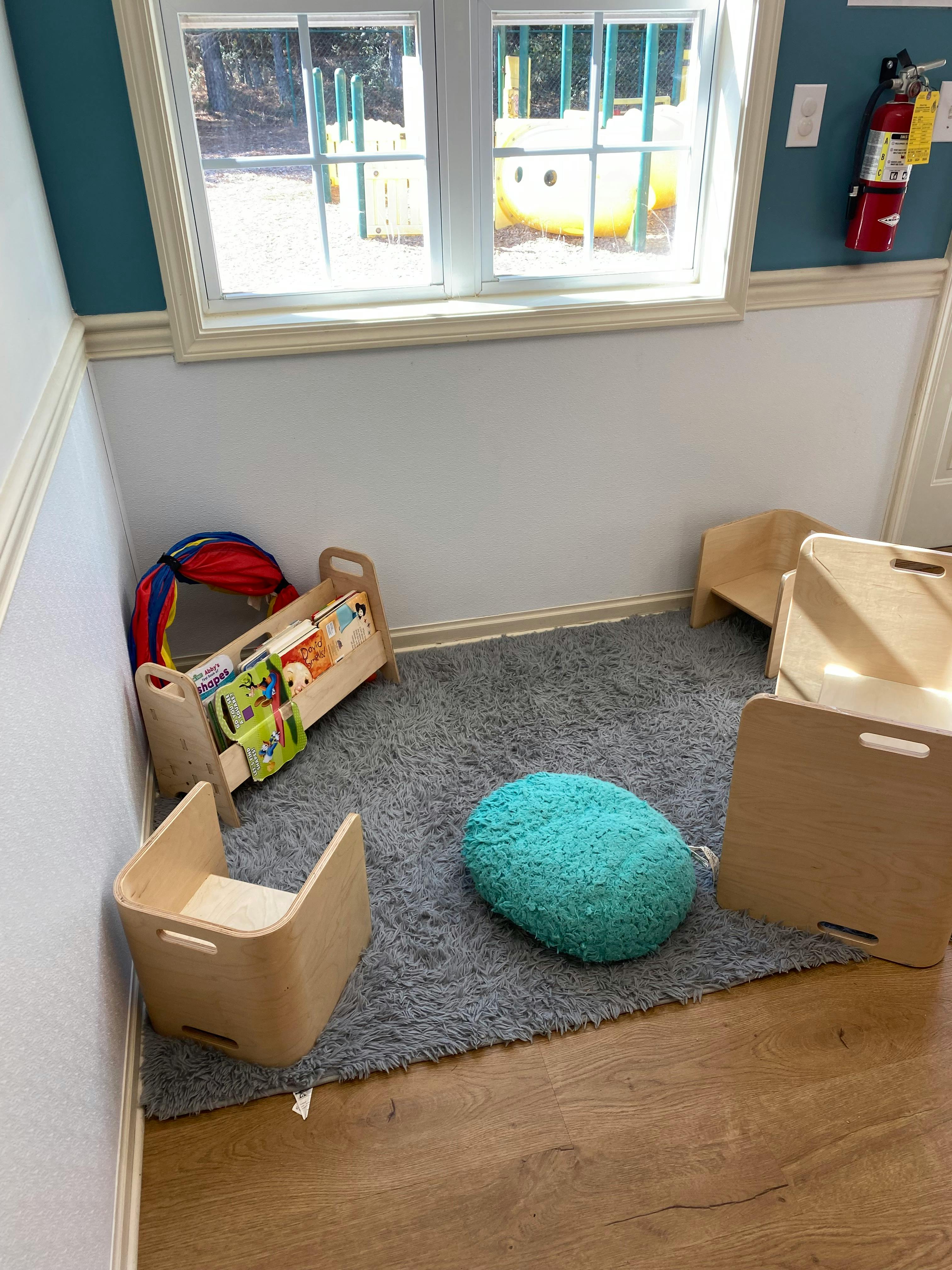 Child's room with windows, play tunnel, small chairs, rug, and fire extinguisher