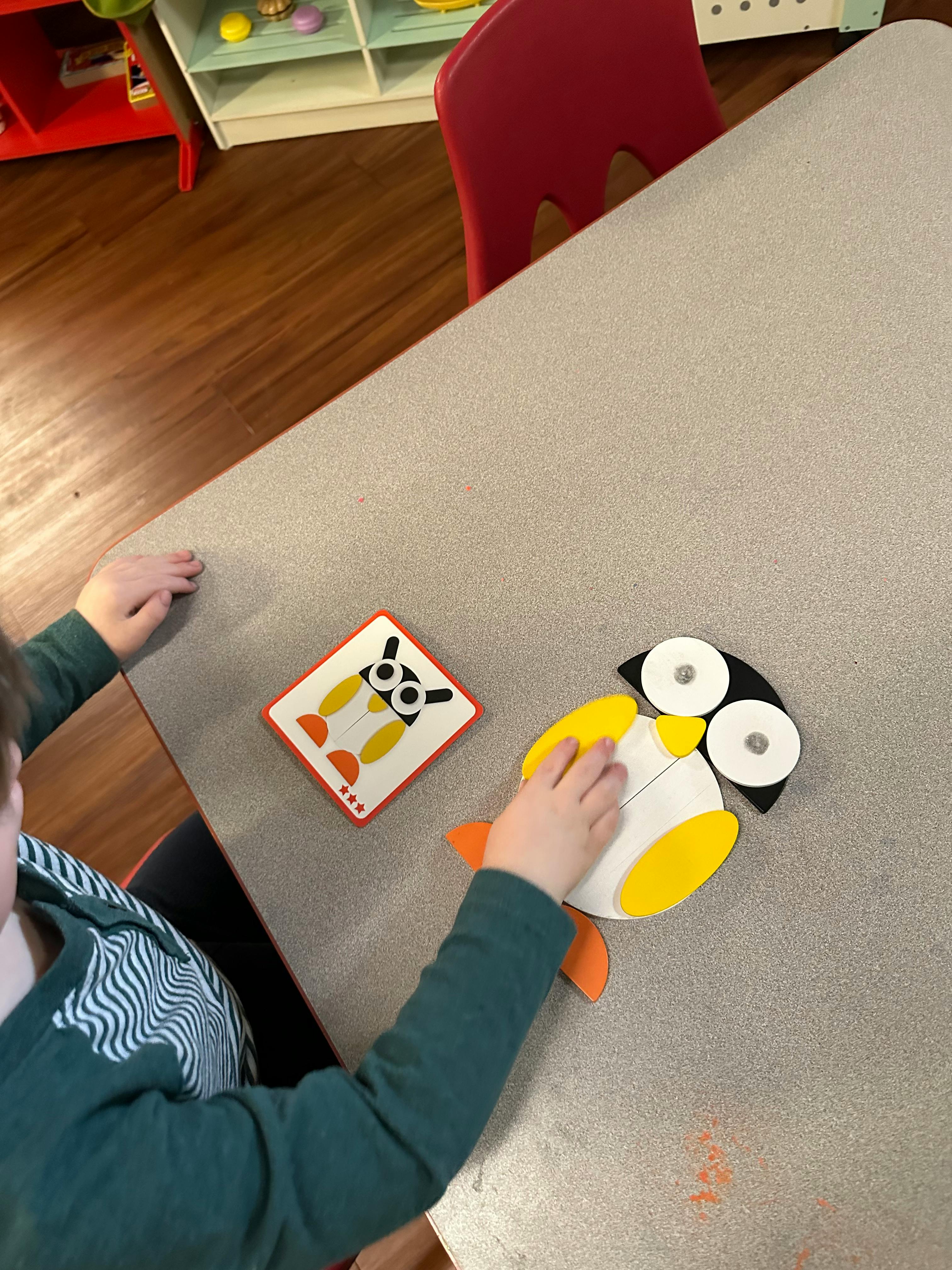 Child playing with a penguin puzzle on a table