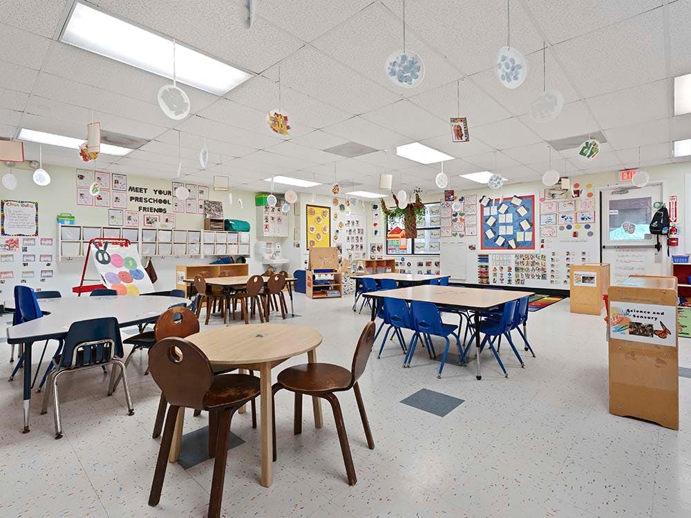 Classroom with small tables and chairs, wall art, and hanging decorations