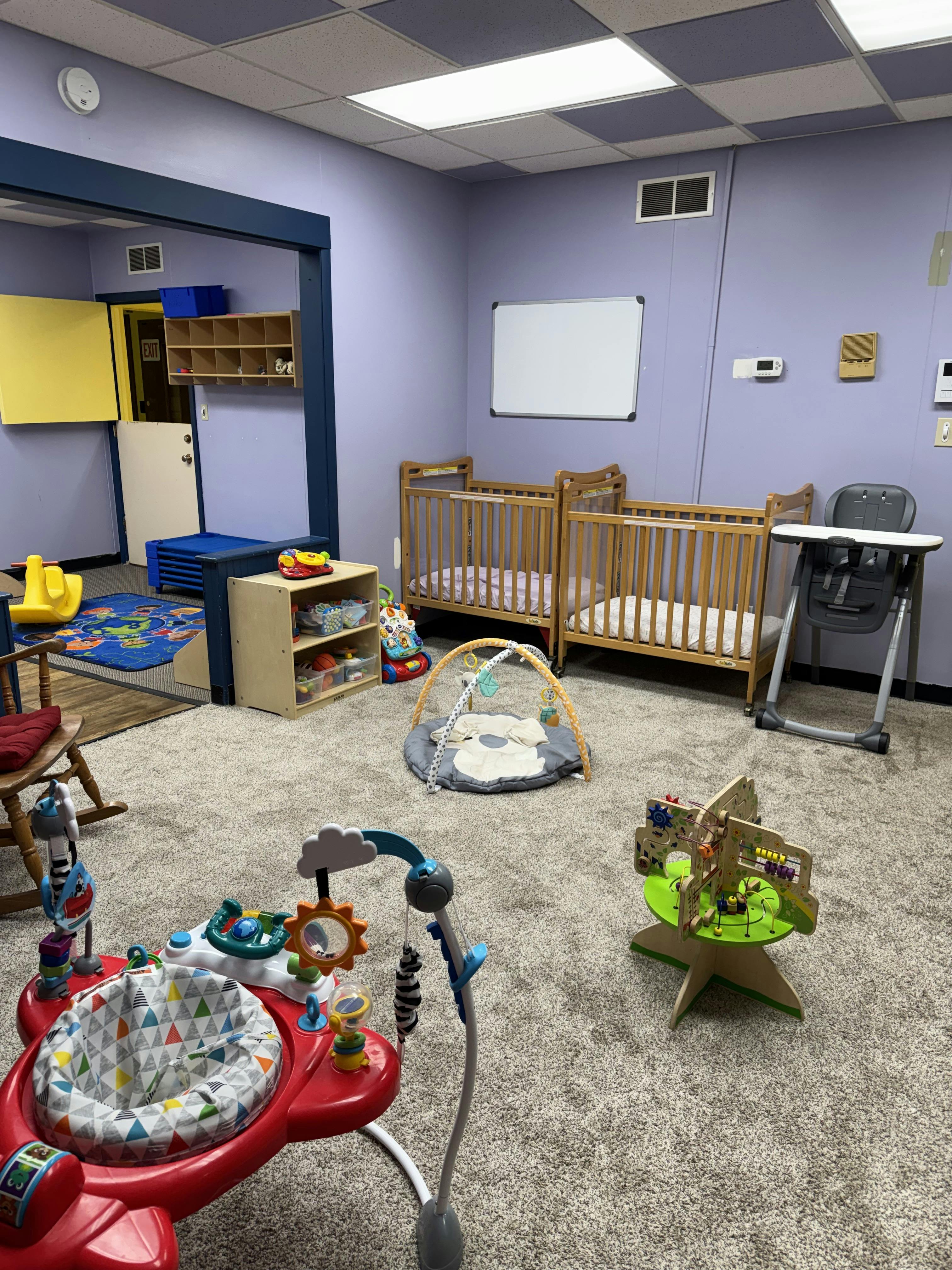 Cribs and infant activity equipment in a daycare room