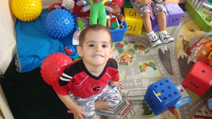 Child sitting on a rug surrounded by toys