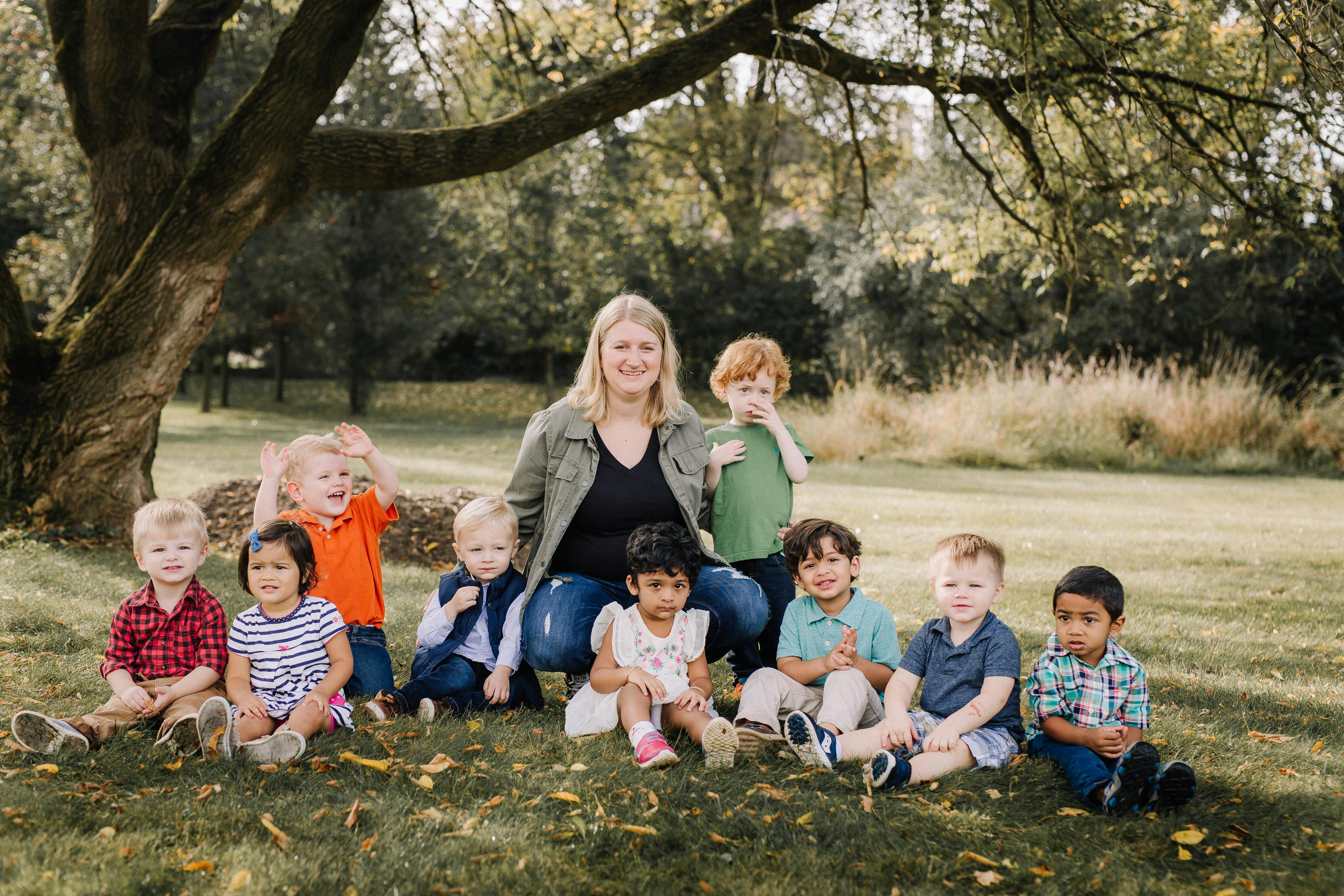 Adult and multiple children sitting on grass outdoors