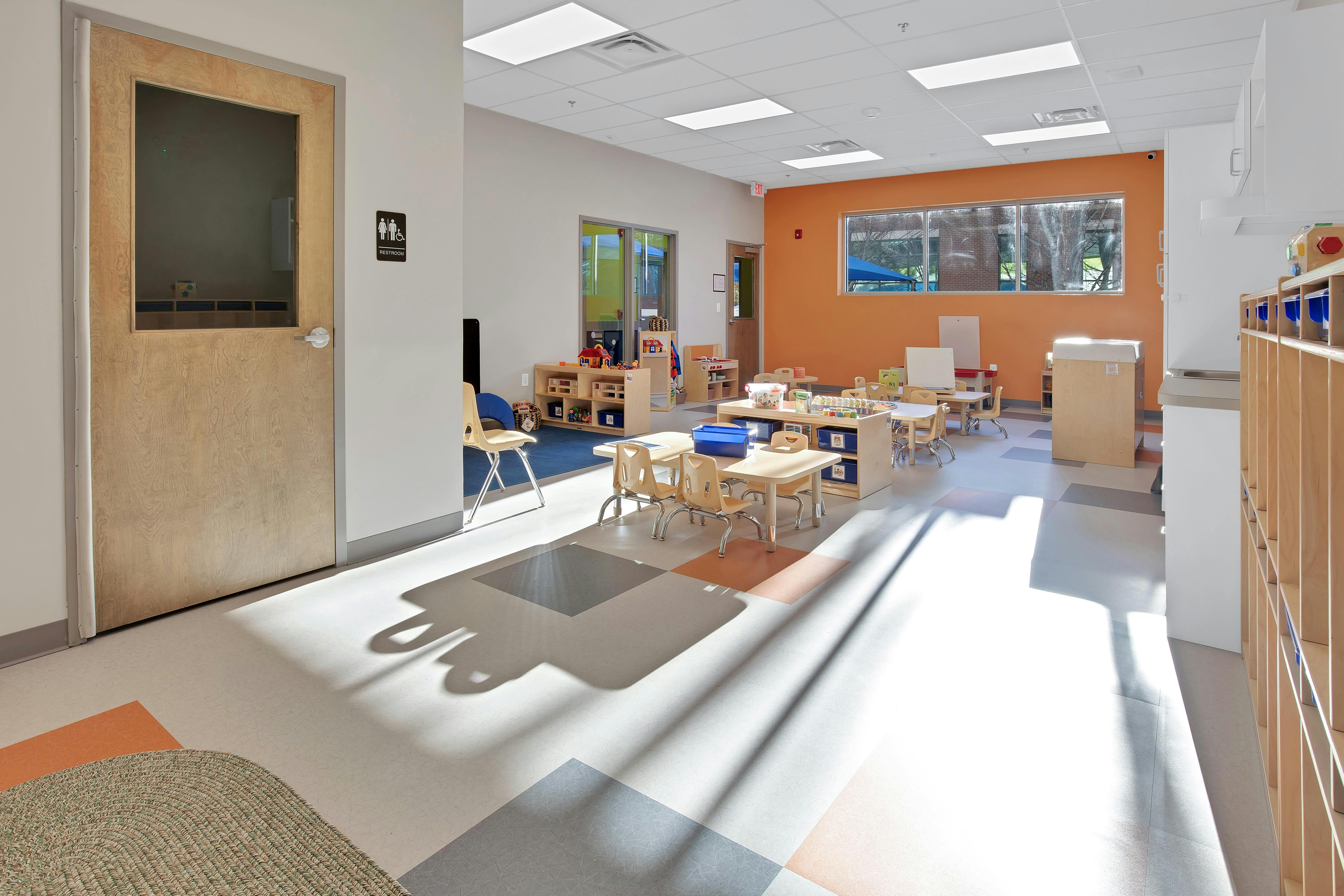 Classroom with small tables, chairs, and play areas