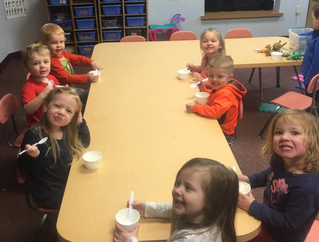 Children sitting at a table with cups and spoons