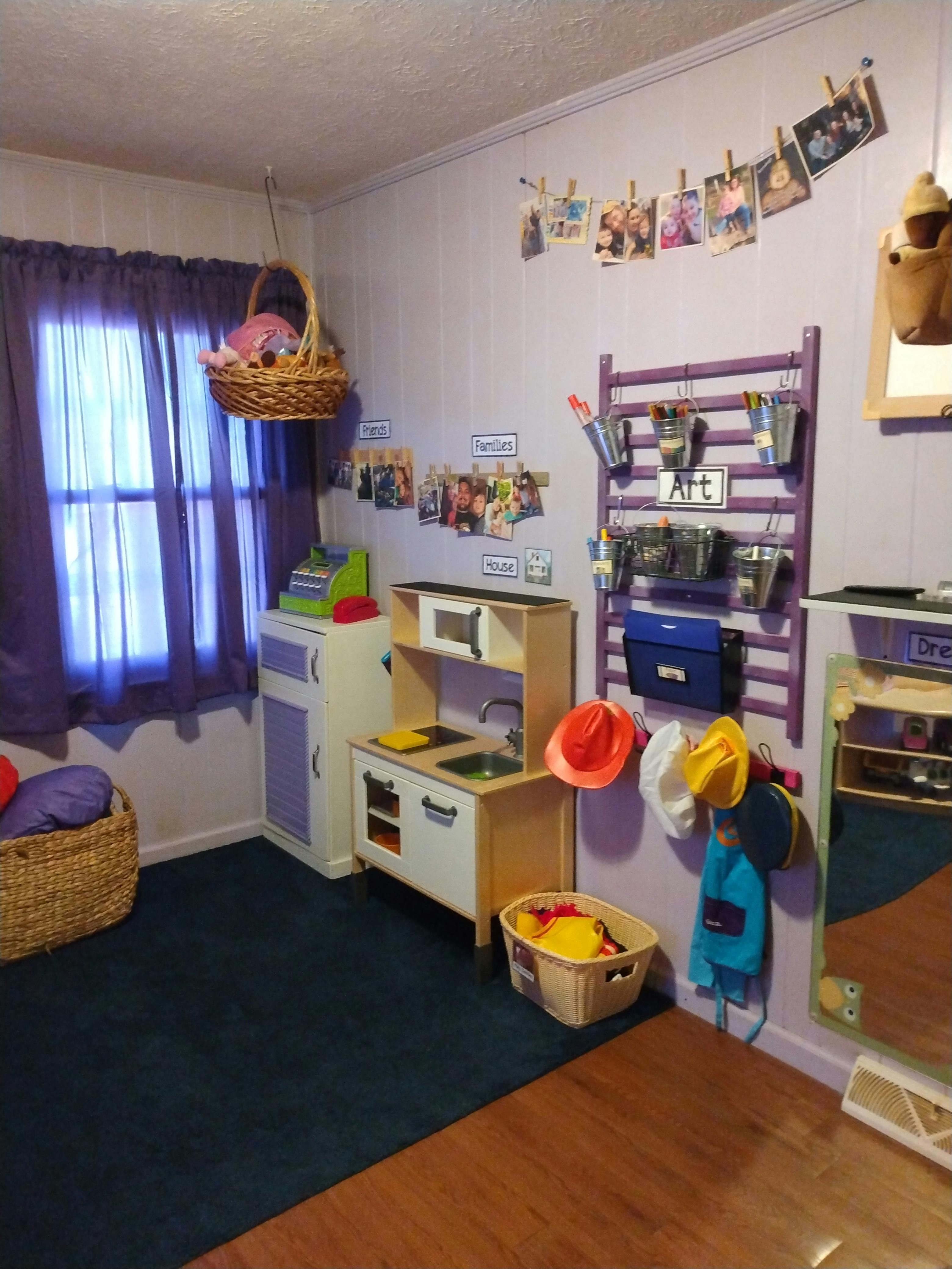 Playroom with toy kitchen, art supplies, and photos on the wall