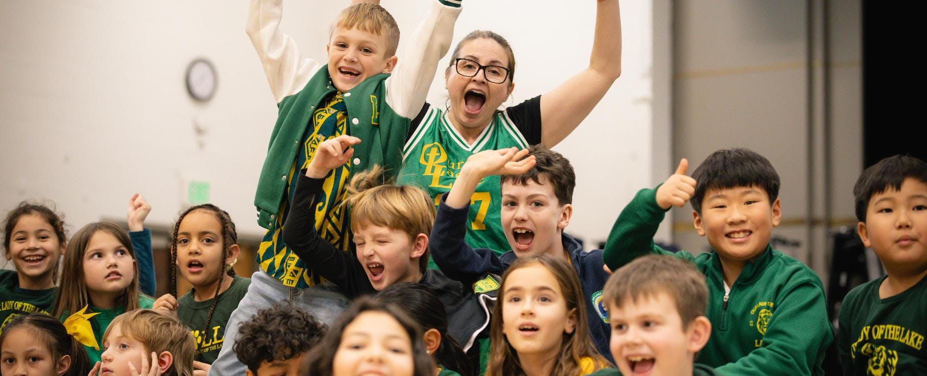 A person and several children cheering with mouths open and arms raised