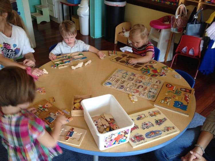 Adults and children playing with puzzles at a round table