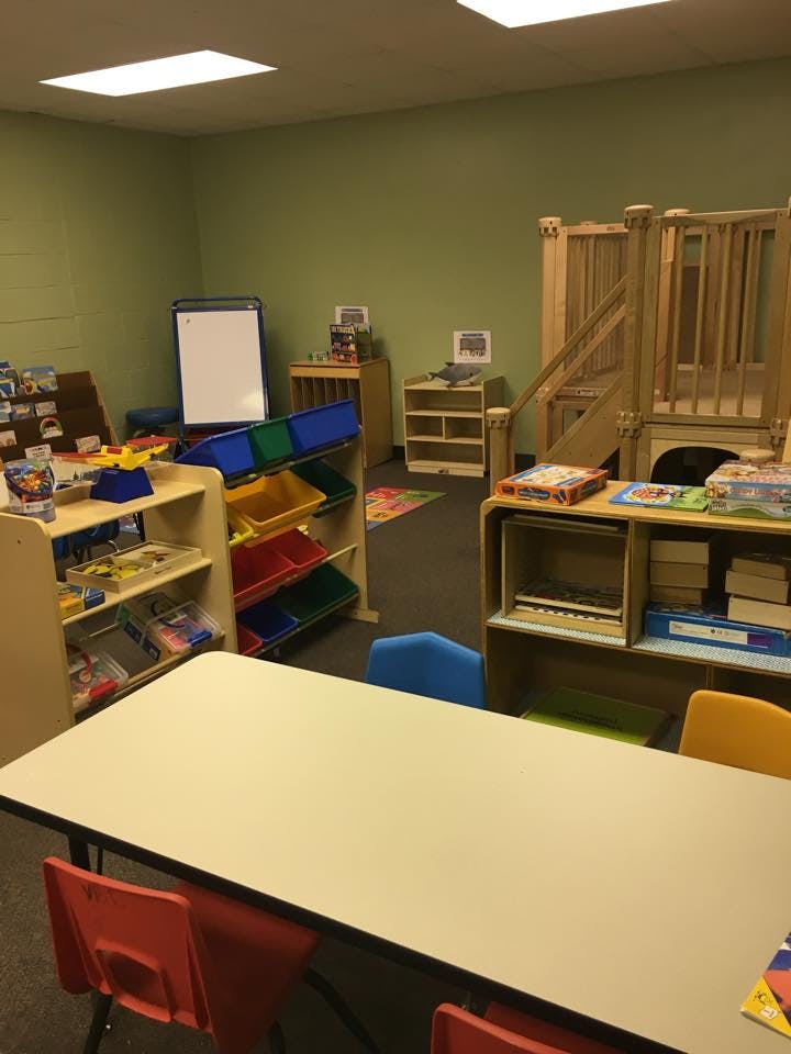 Classroom with tables, chairs, shelves, and a wooden play structure