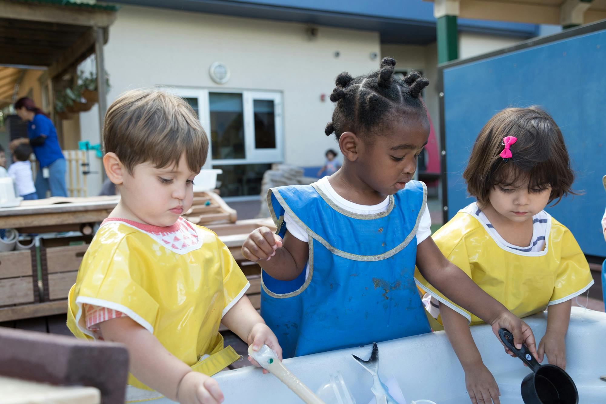 Three children in smocks playing with water in a trough
