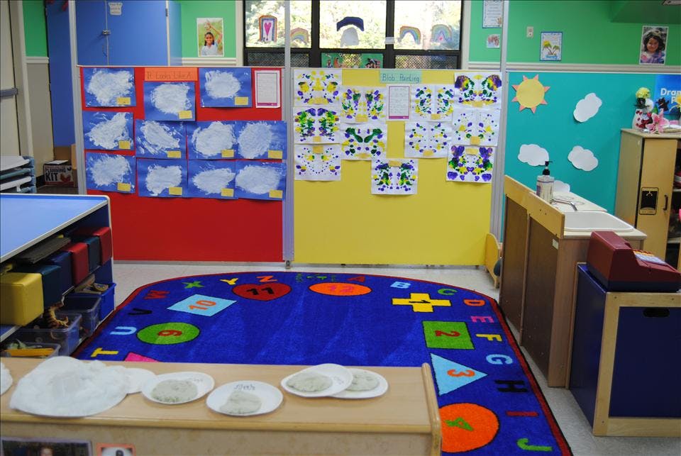 Classroom with children's artwork displayed and a colorful rug