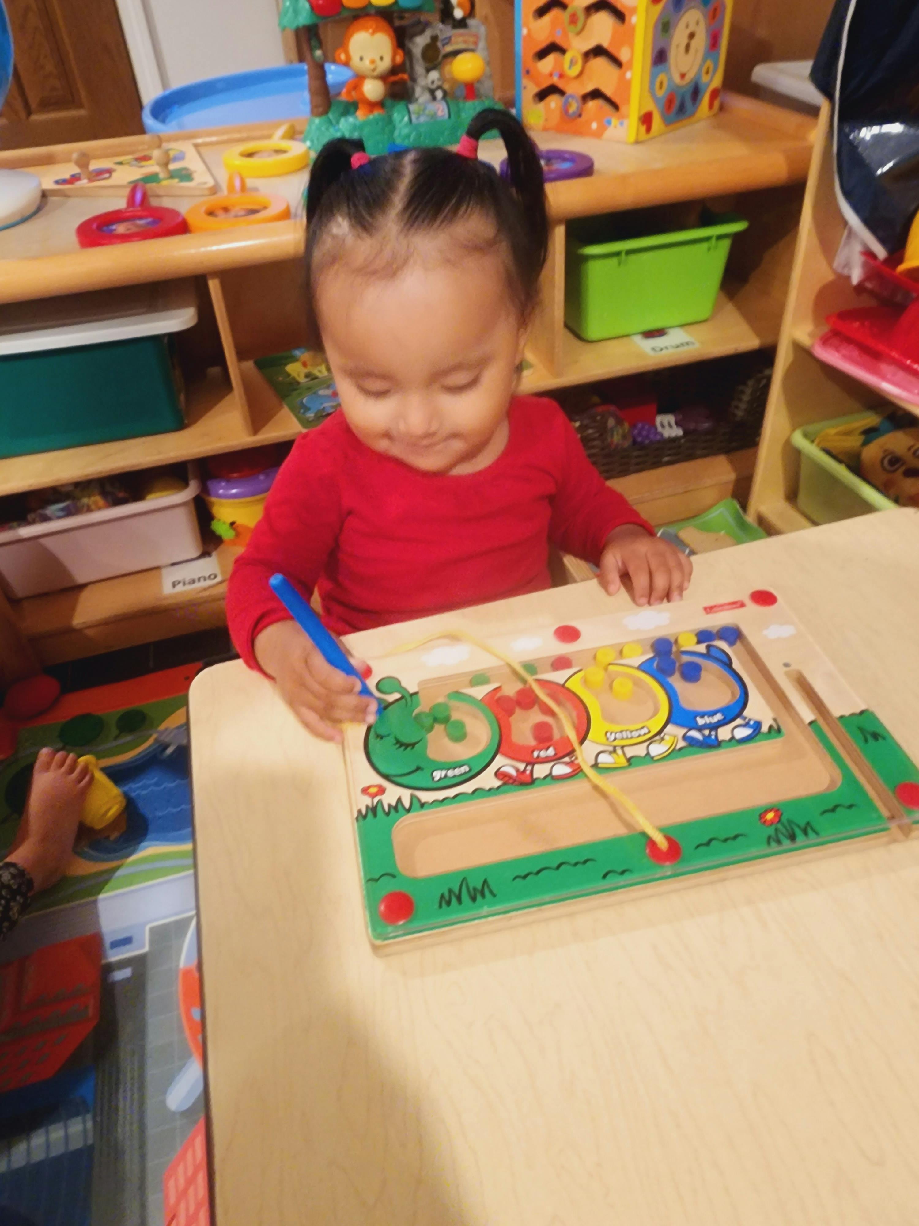 Child playing with a wooden magnetic maze toy at a table