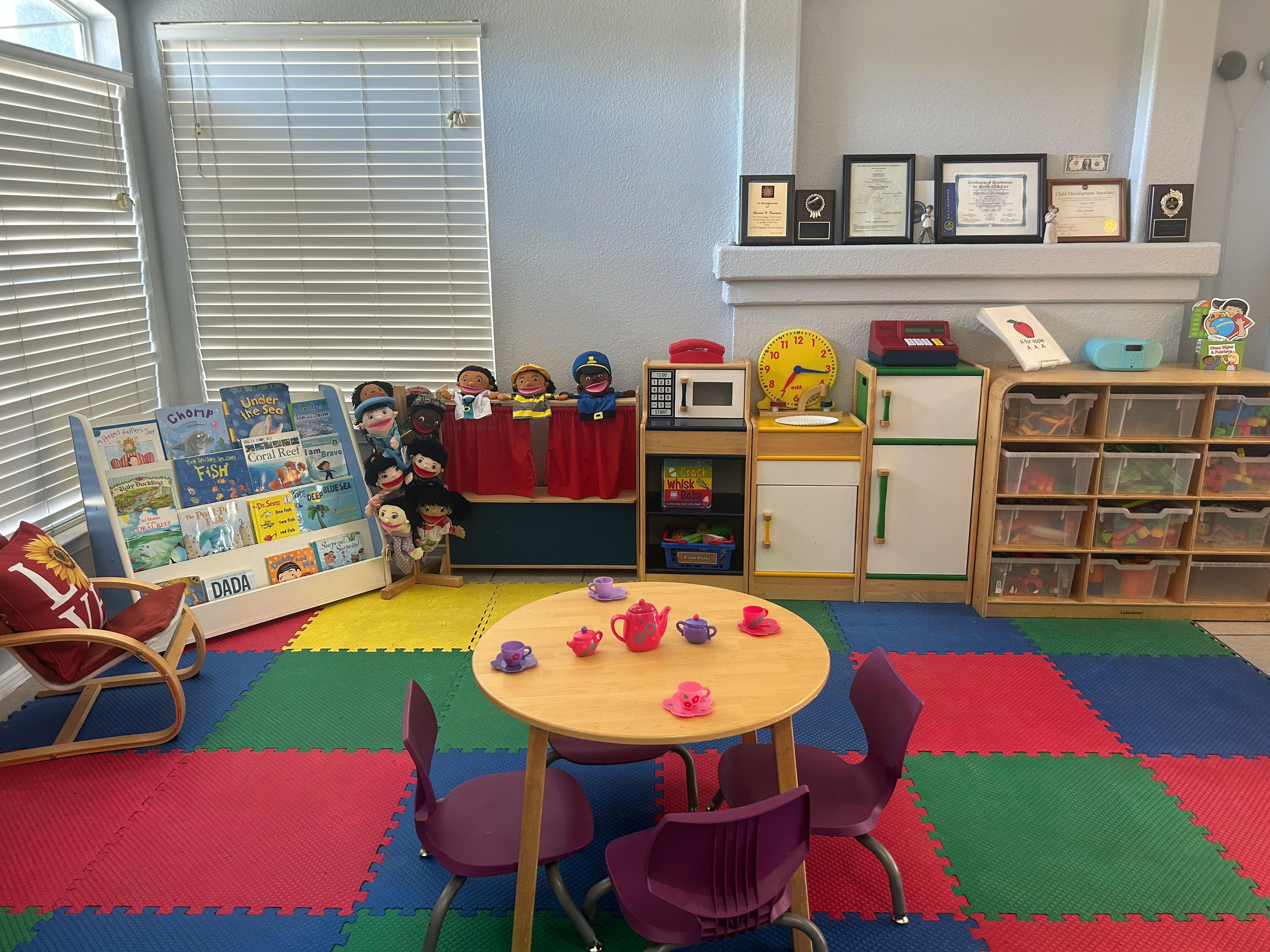 Playroom with small table and chairs, toy kitchen, and book display