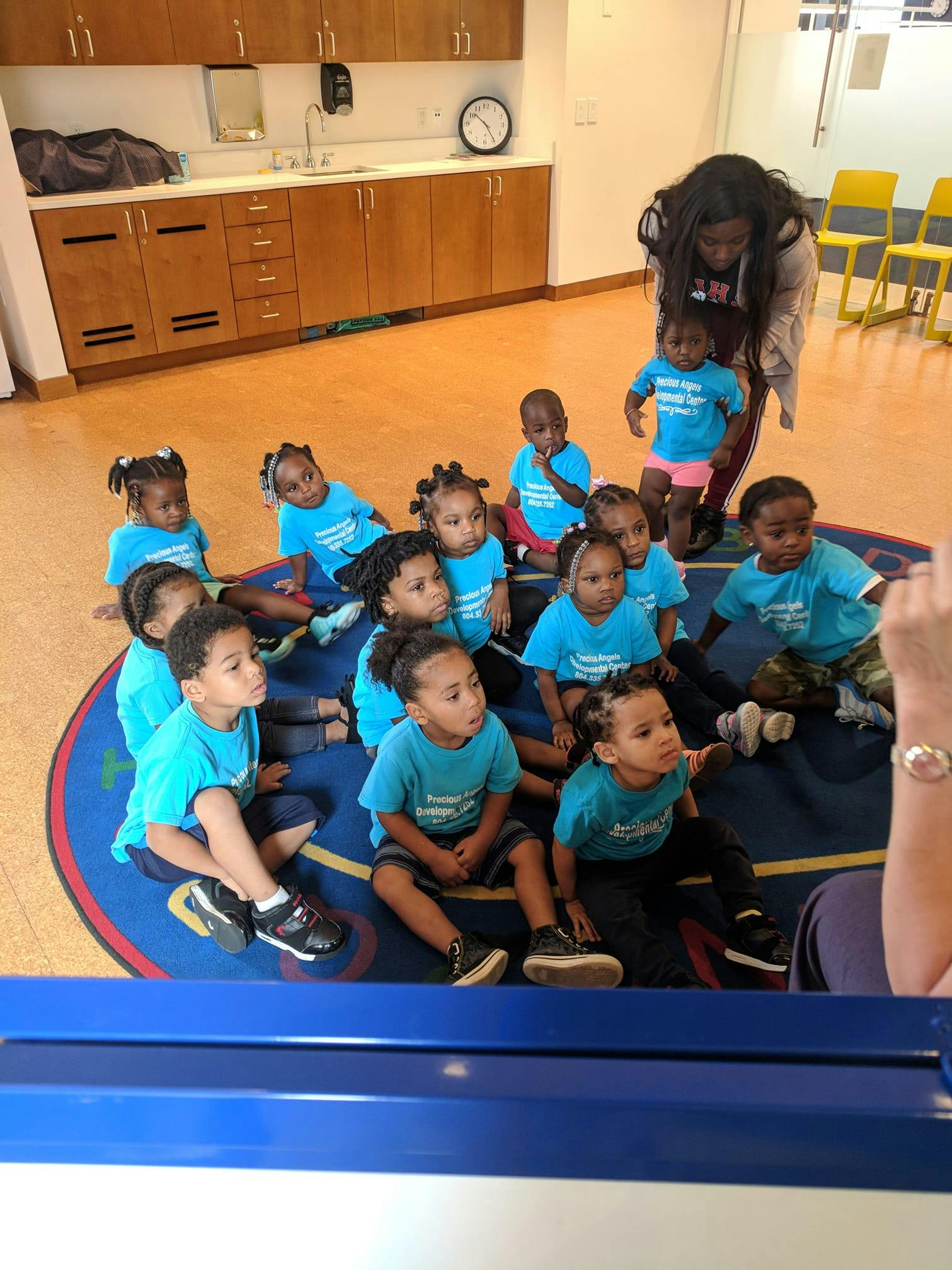 Adult and children sitting on a rug in a classroom