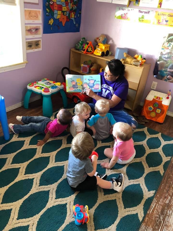 Person reading a book to a group of children in a classroom