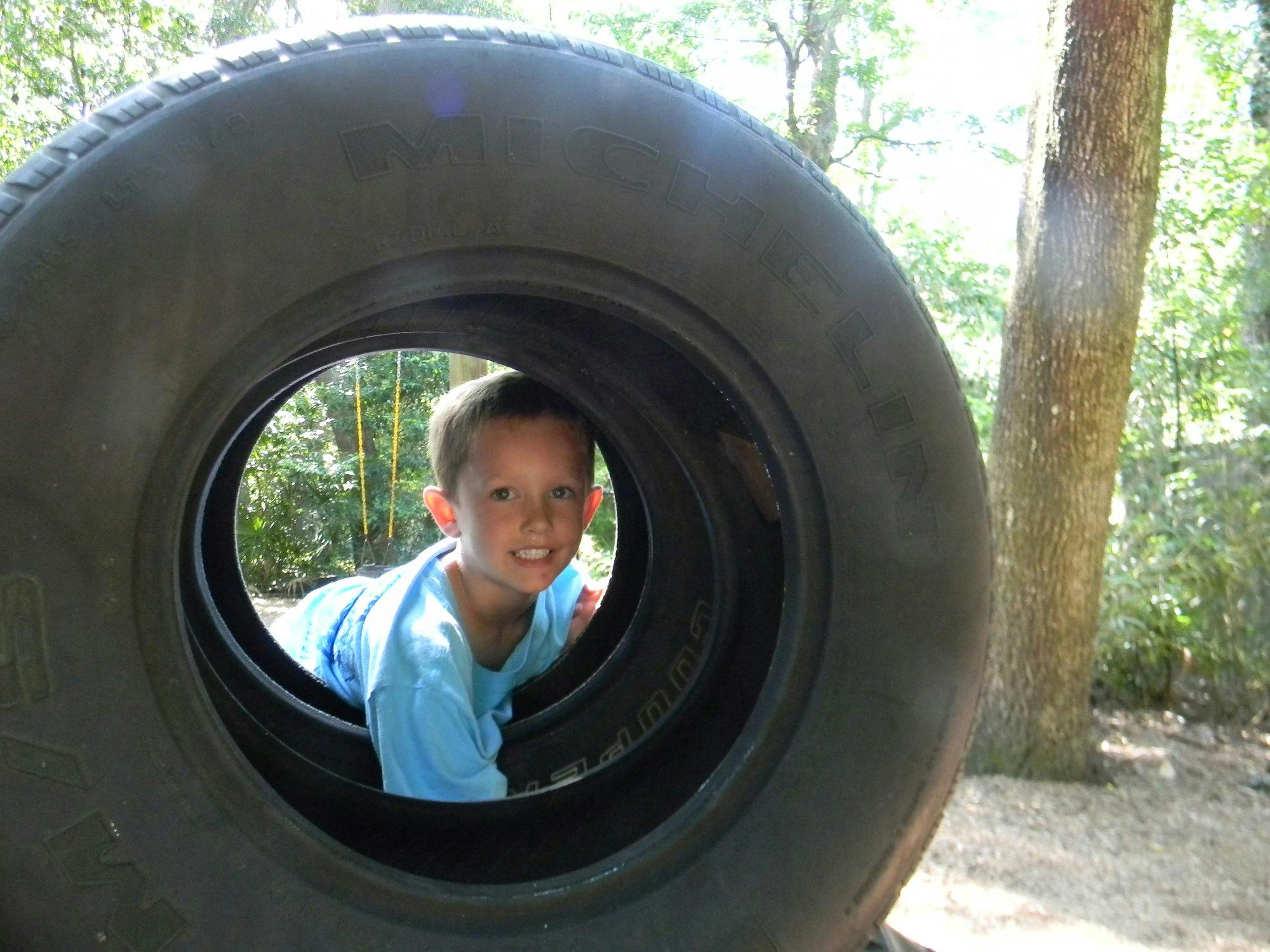 Child looking through a large tire