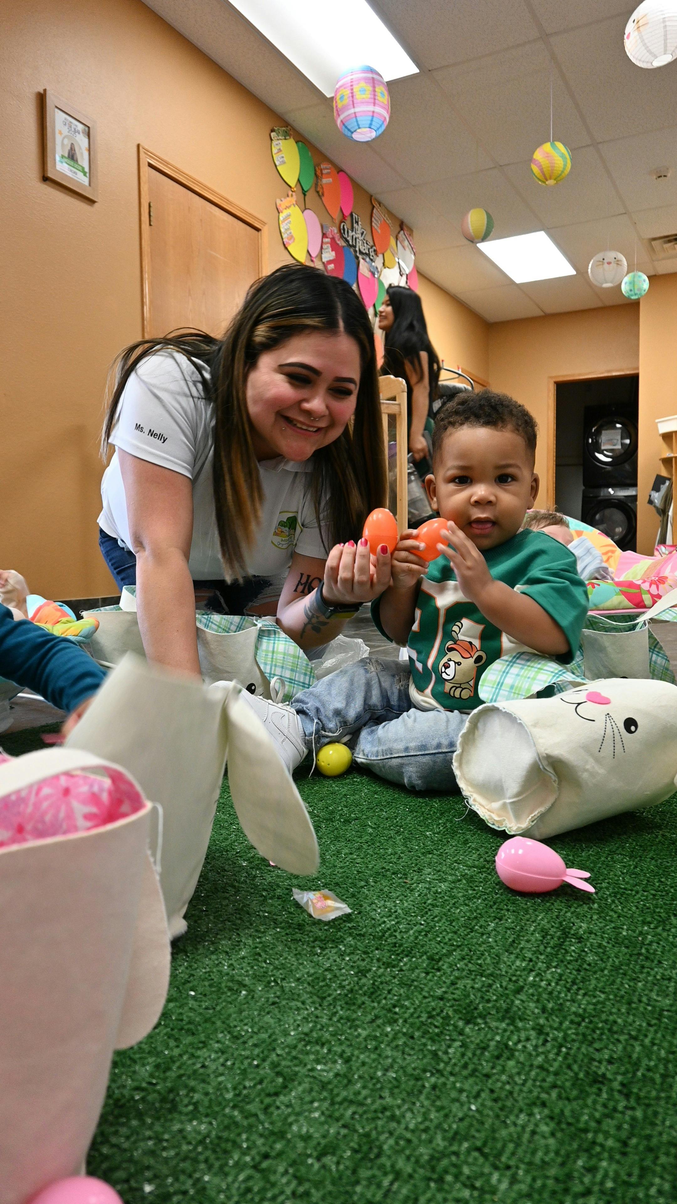Adult and child on floor, child holding orange plastic eggs