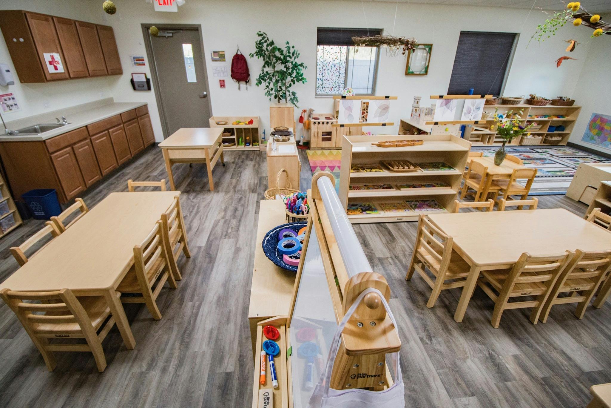 Empty classroom with small wooden tables and chairs