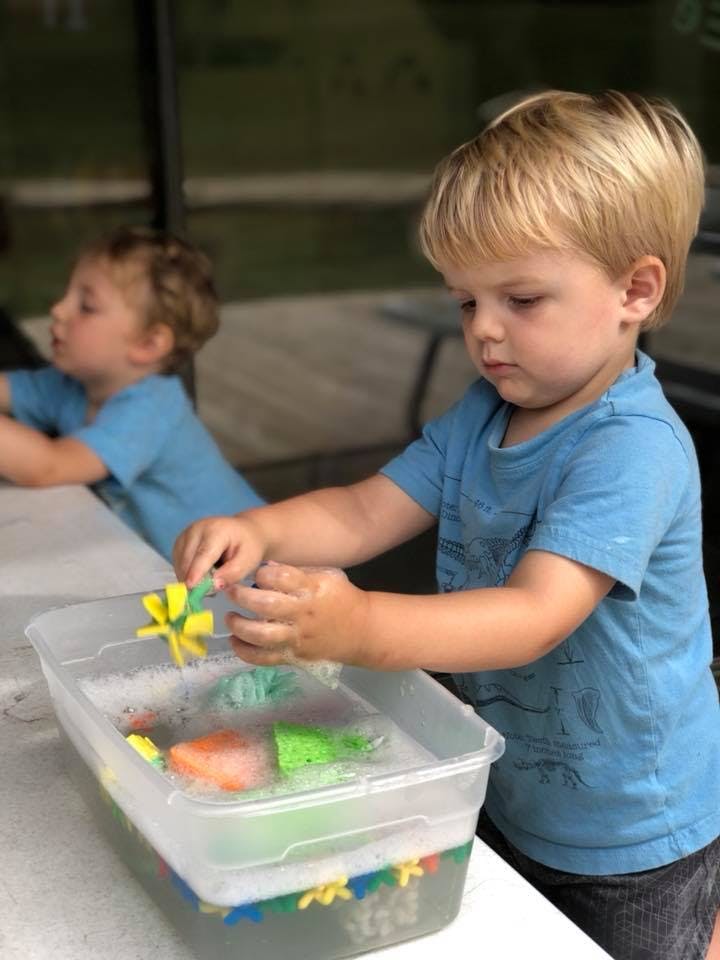 Child playing with toys in a container of water