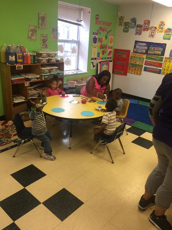 Adult and children sitting at a table in a classroom