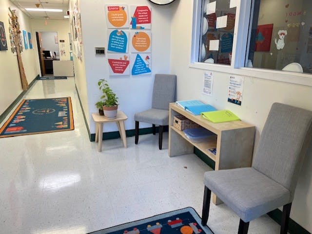 Hallway with chairs, a small table with a plant, and a wooden shelf with items