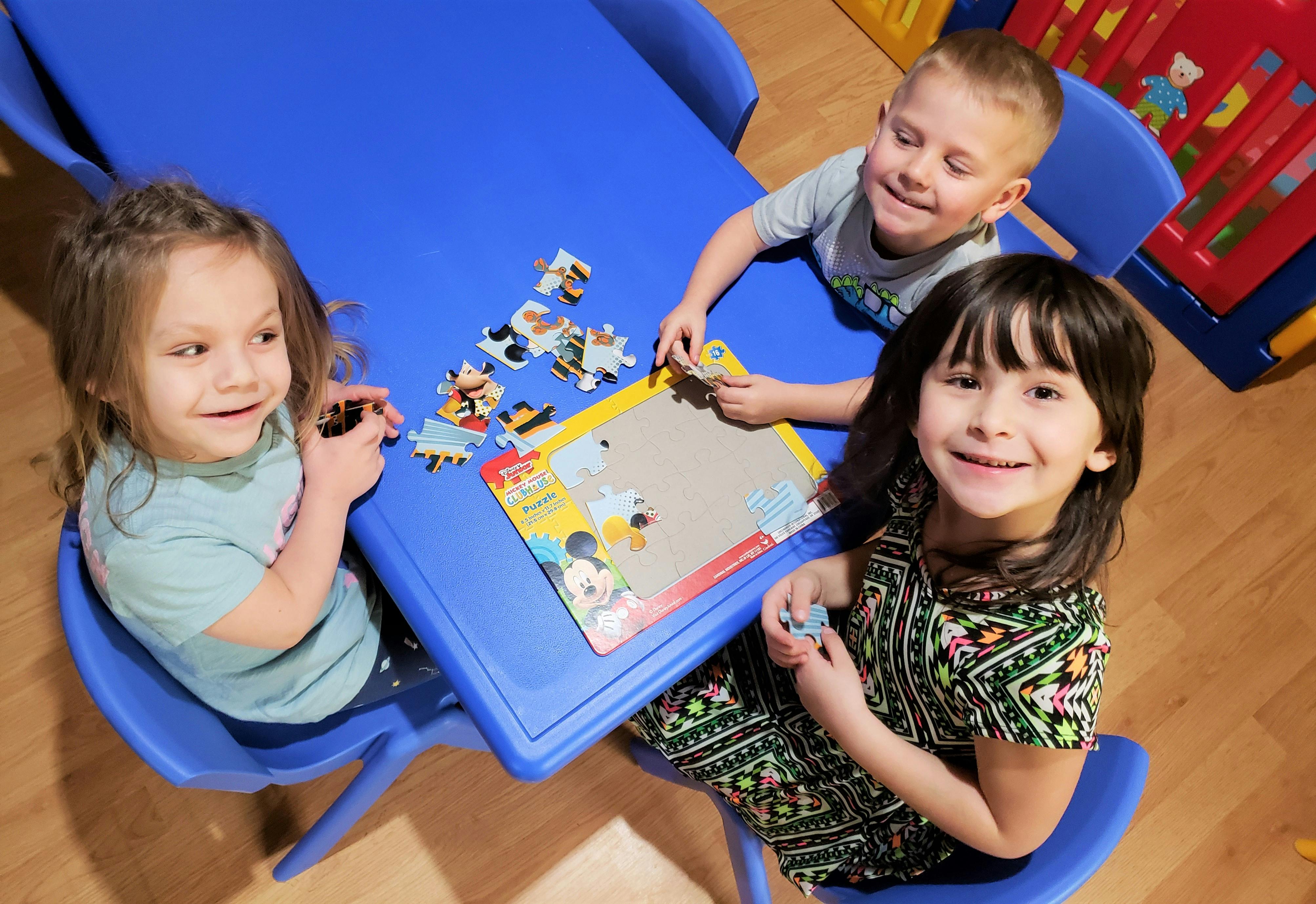 Three children at a table doing a puzzle