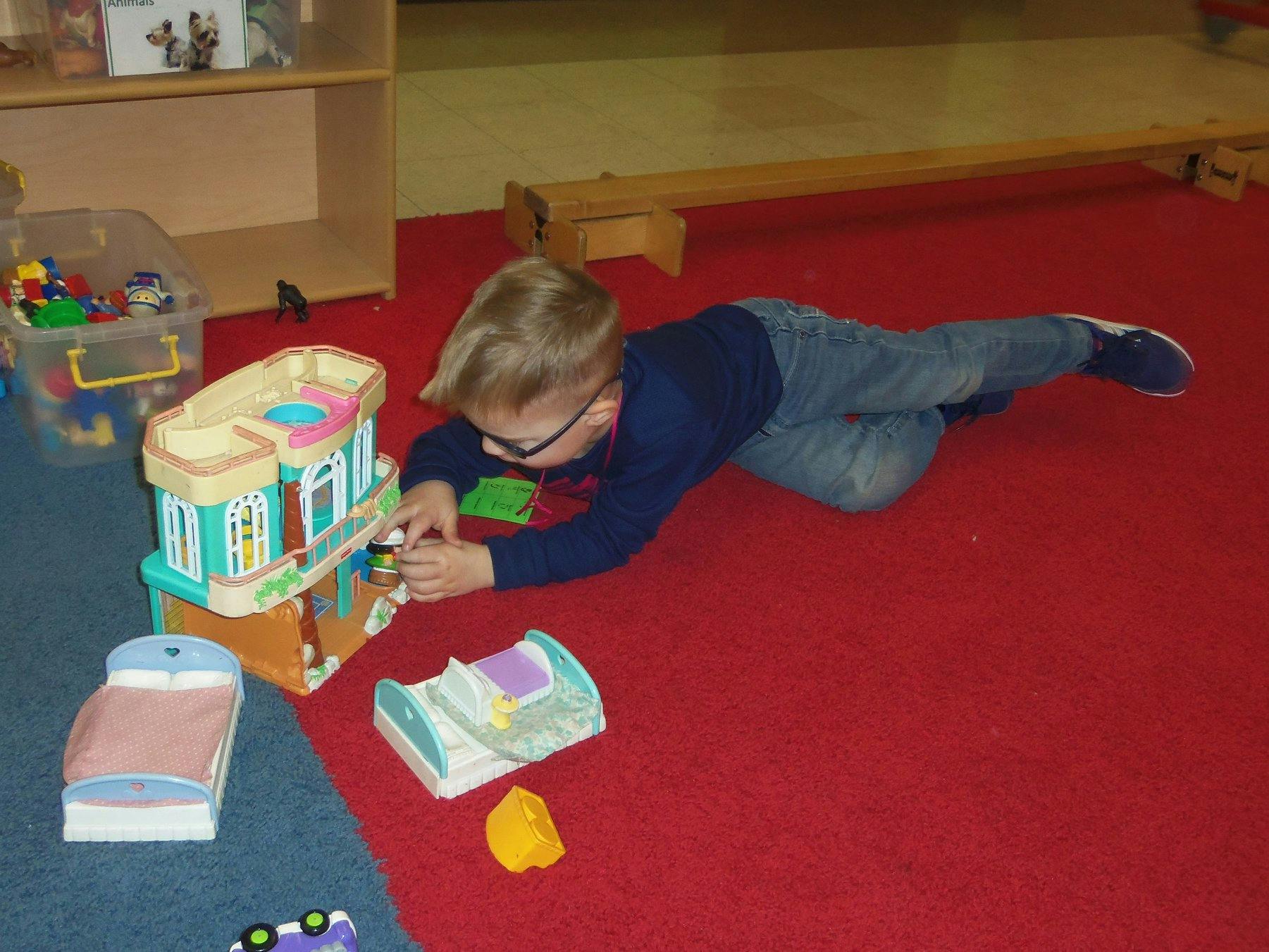 Child playing with a toy house on the floor