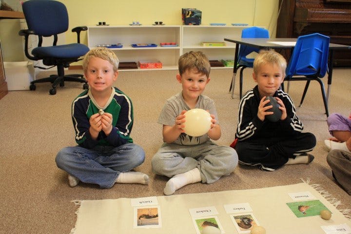 Three children sitting on the floor holding objects