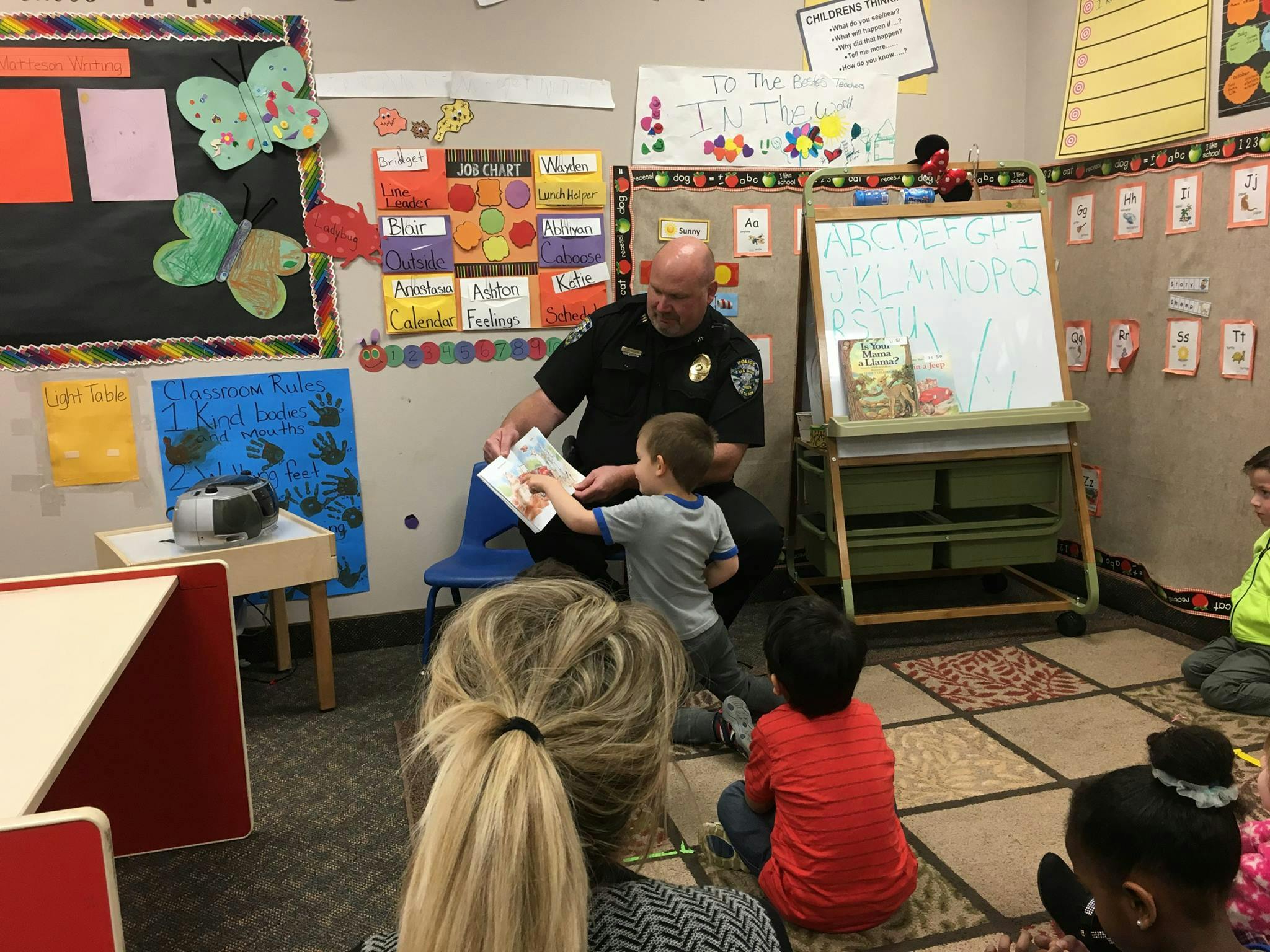 Person in uniform reading a book to children in a classroom