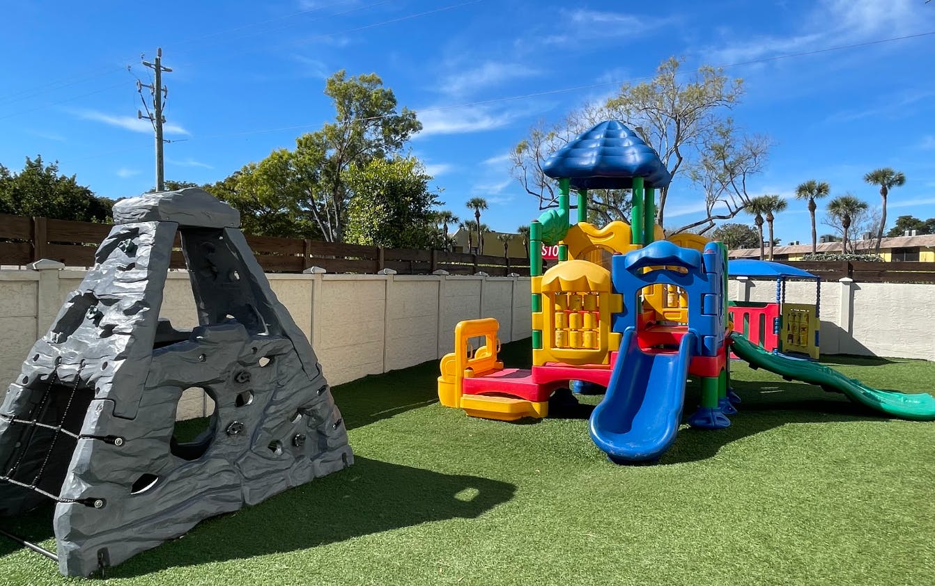 Colorful outdoor playground with climbing structure and slides on artificial turf