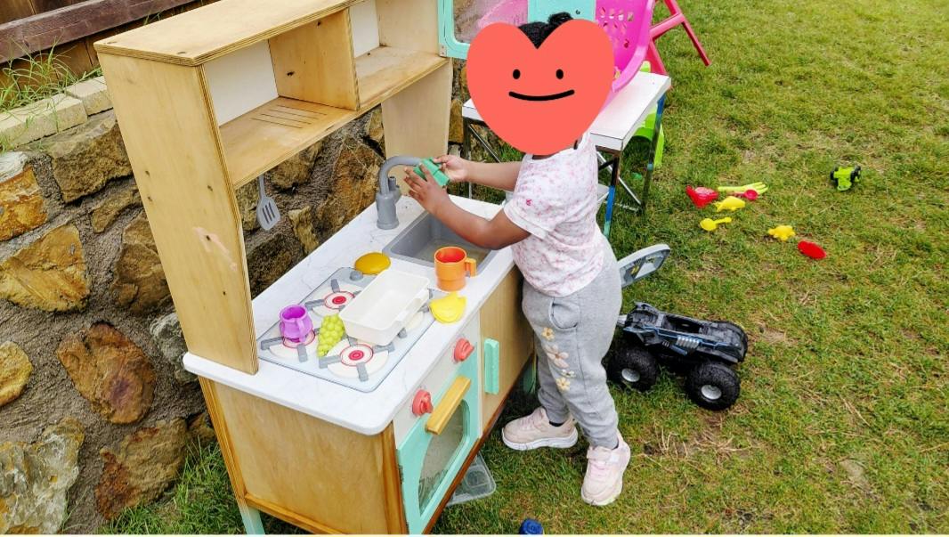 Child playing with a toy kitchen set outdoors
