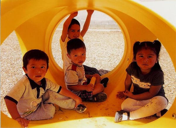 Four children sitting inside a yellow tunnel on a playground