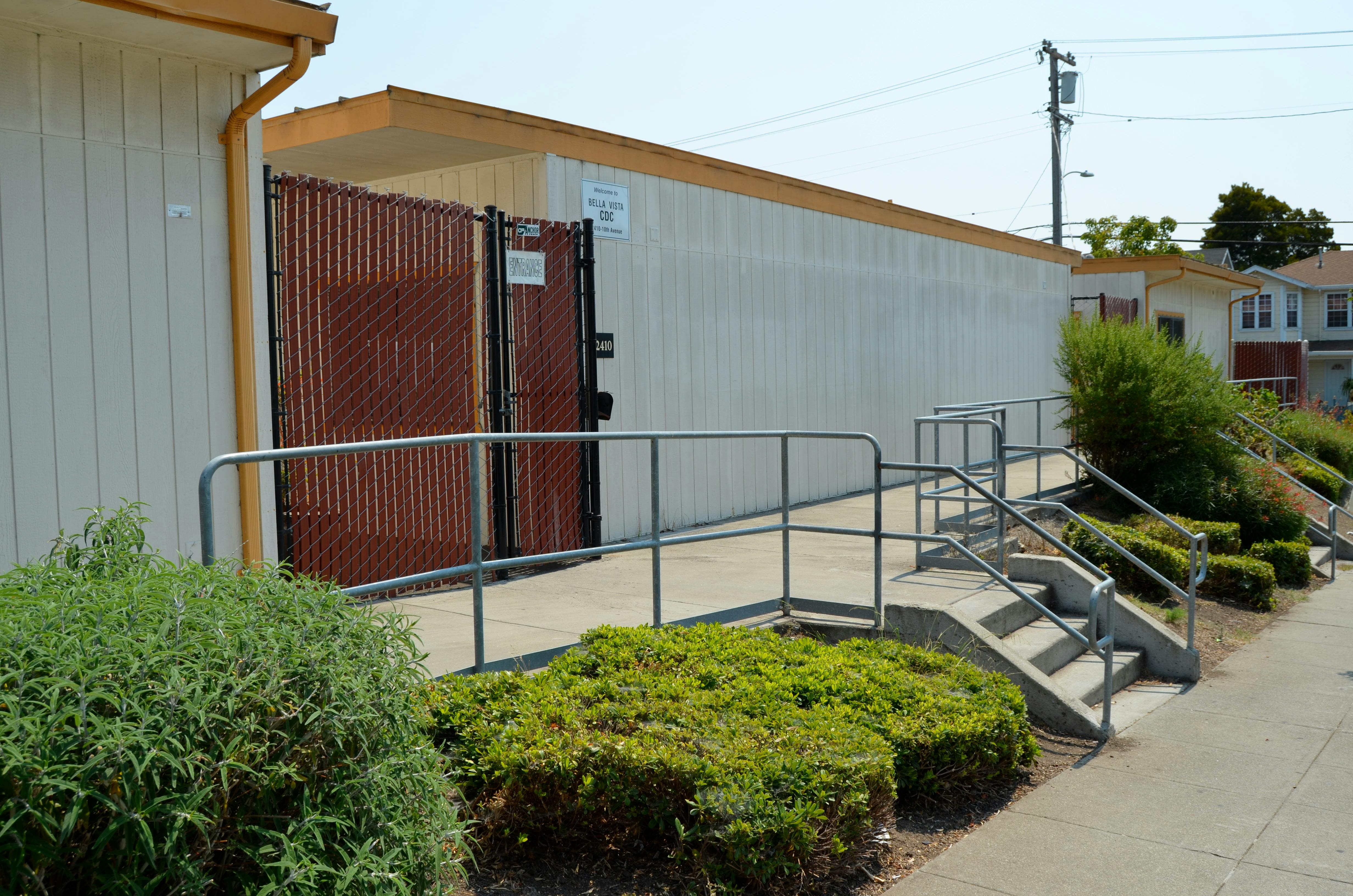 Building exterior with a ramp, stairs, and a fence