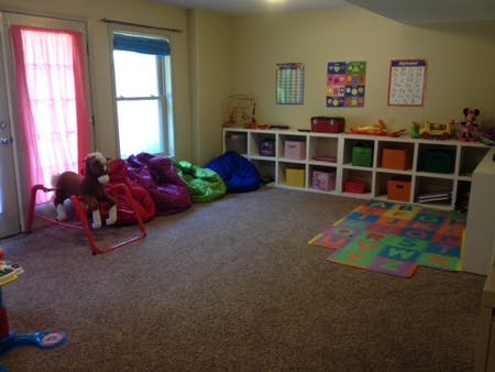 Playroom with beanbag chairs, toy shelf, and colorful mat