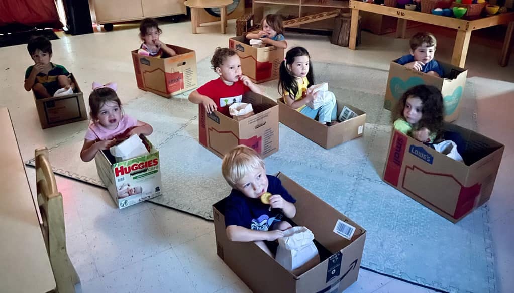 Multiple children sitting in cardboard boxes