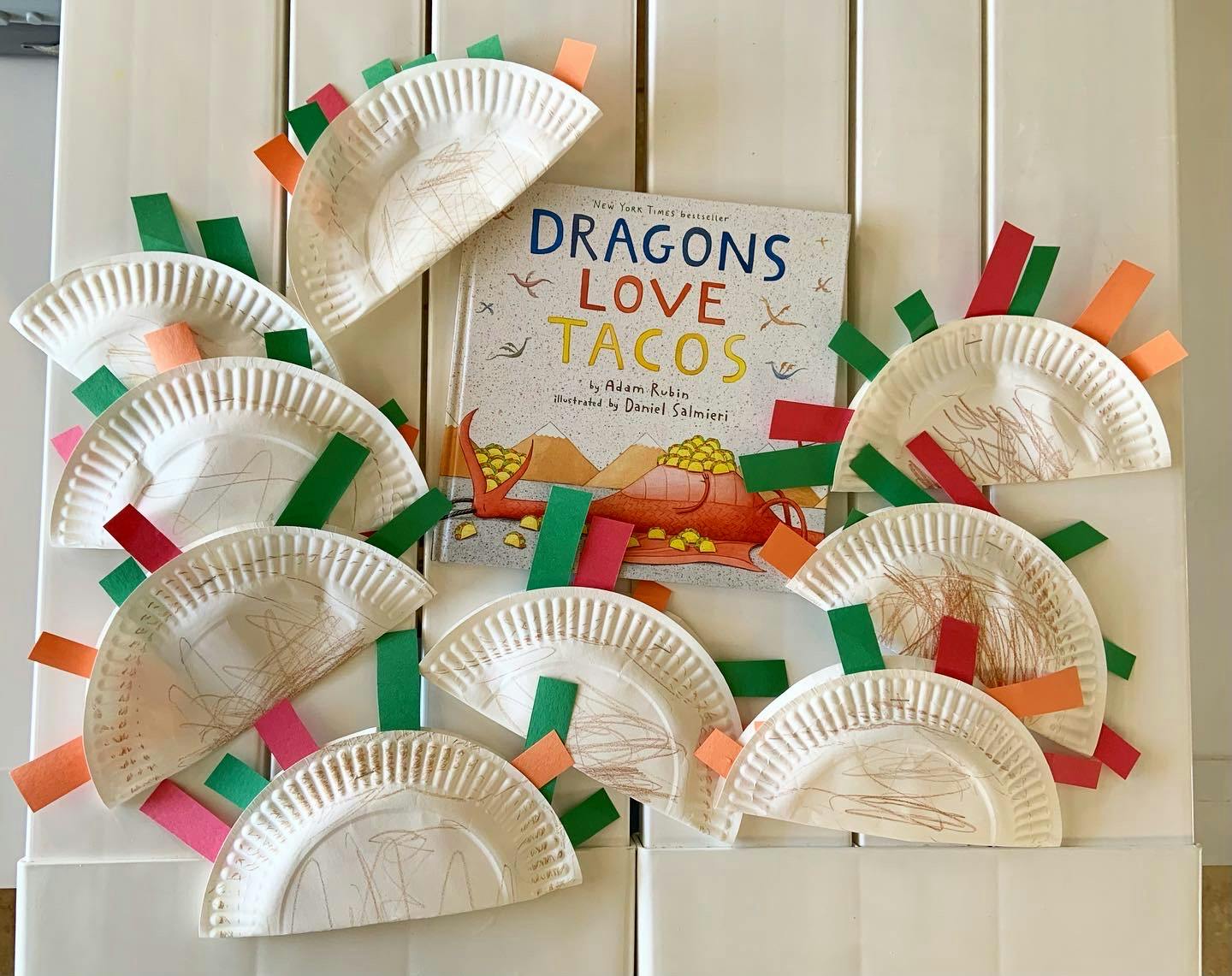 Paper plate tacos with colorful paper strips and a book titled "Dragons Love Tacos"