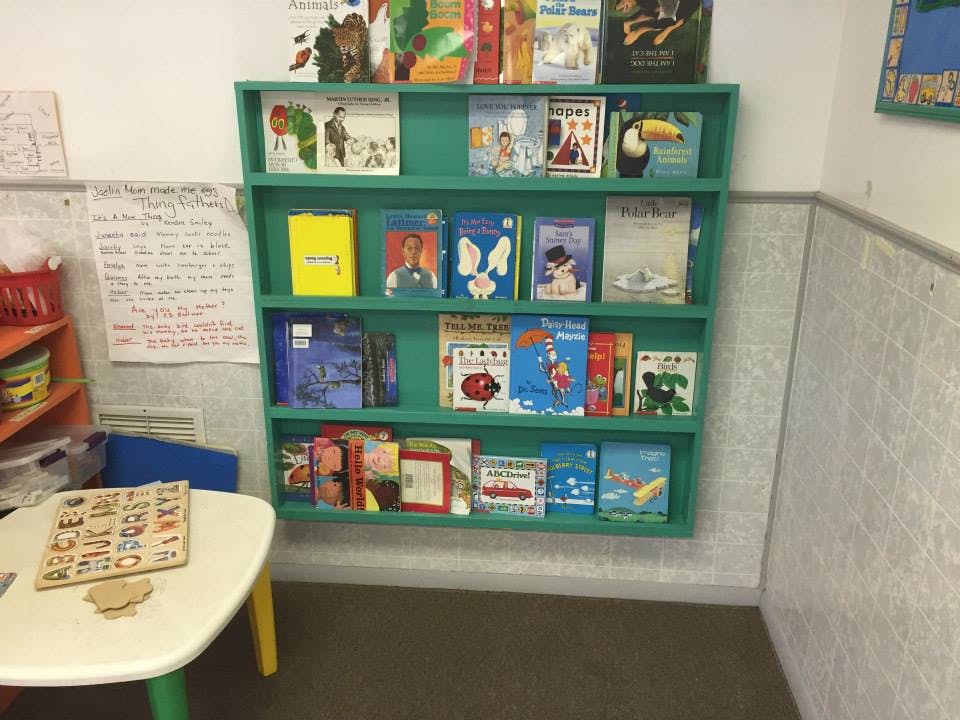 Green bookshelf filled with children's books in a classroom