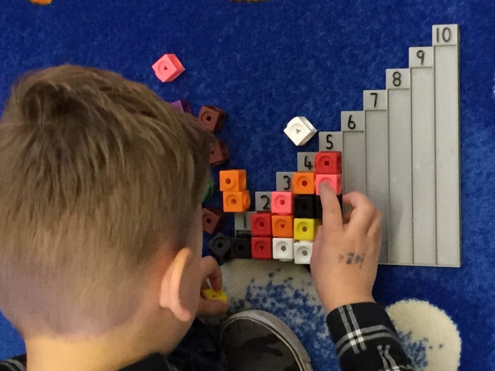 Child playing with colorful counting cubes and a number board