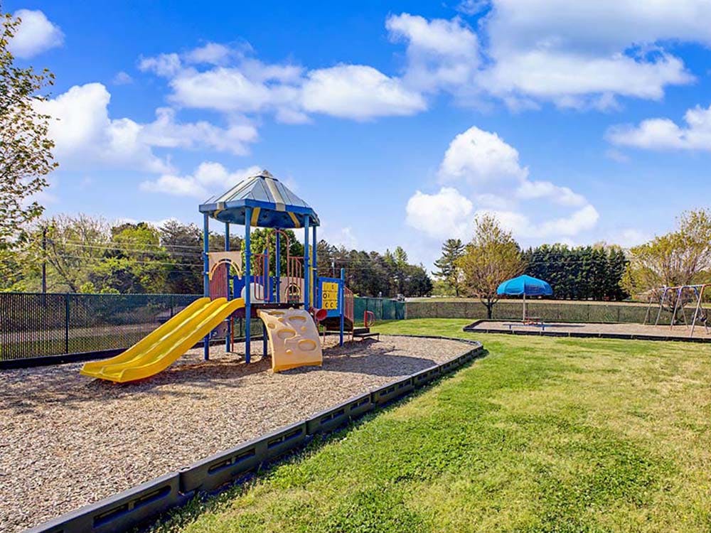 A children's playground with a yellow slide and blue and yellow play structure
