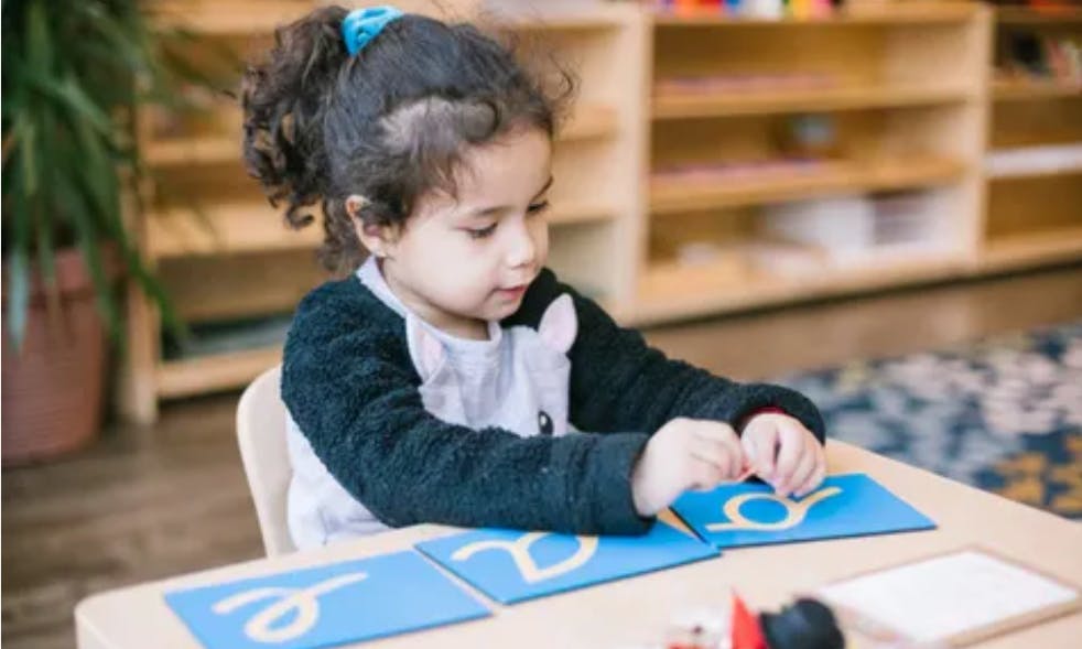 Child at a table tracing letters on blue cards