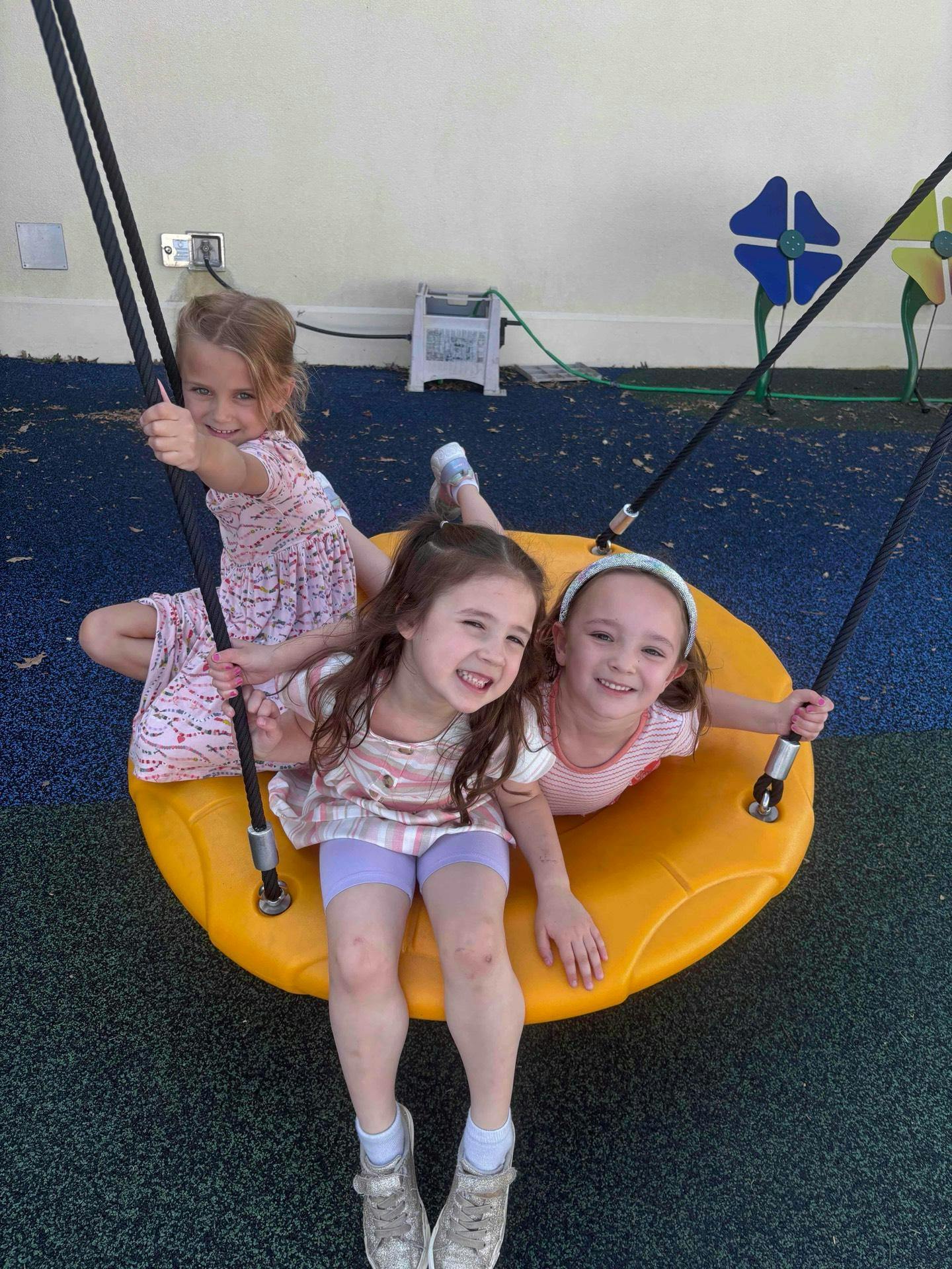 Three children on a yellow swing