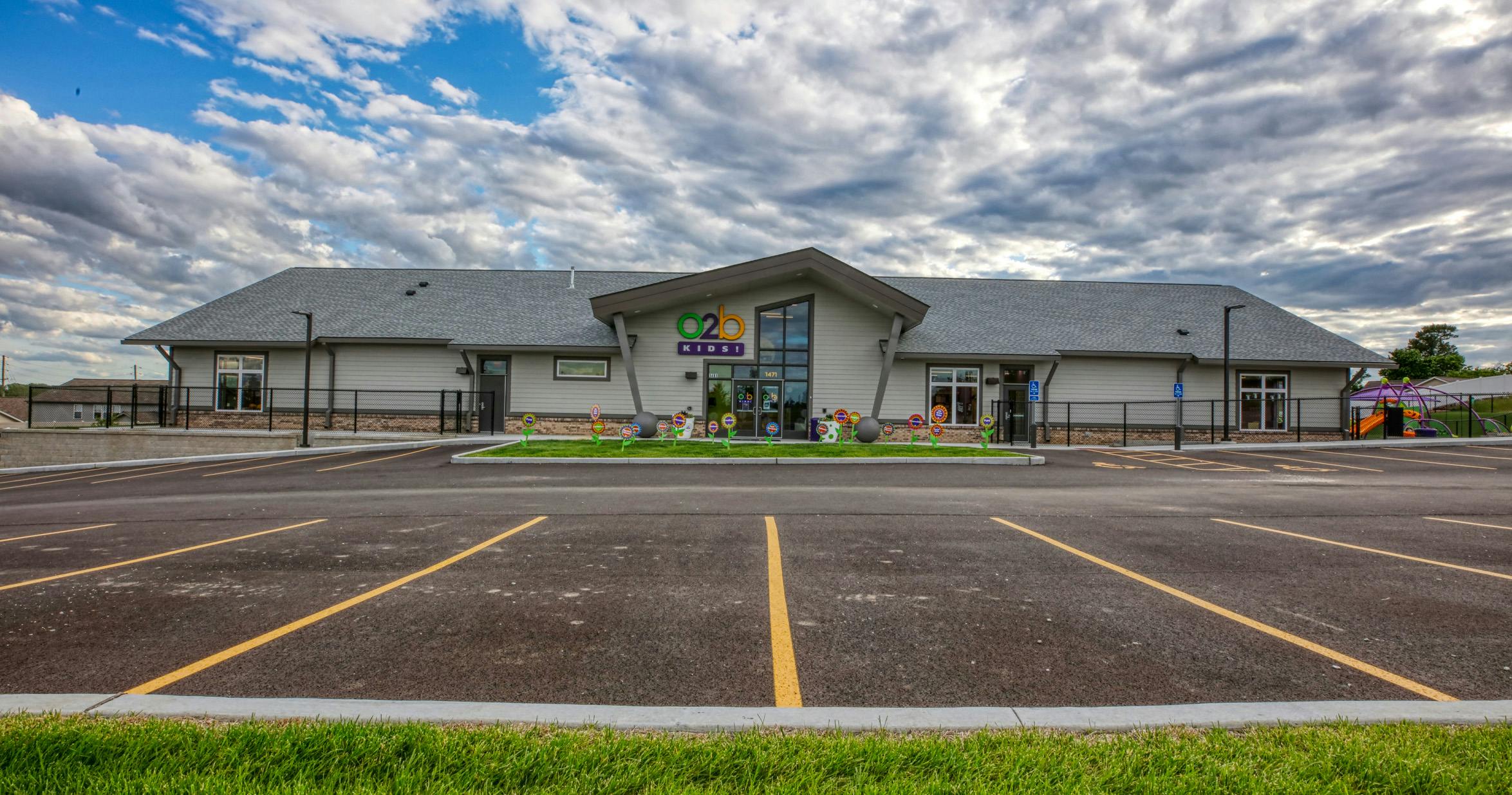 A low-angle shot of a gray childcare facility with an O2B Kids sign