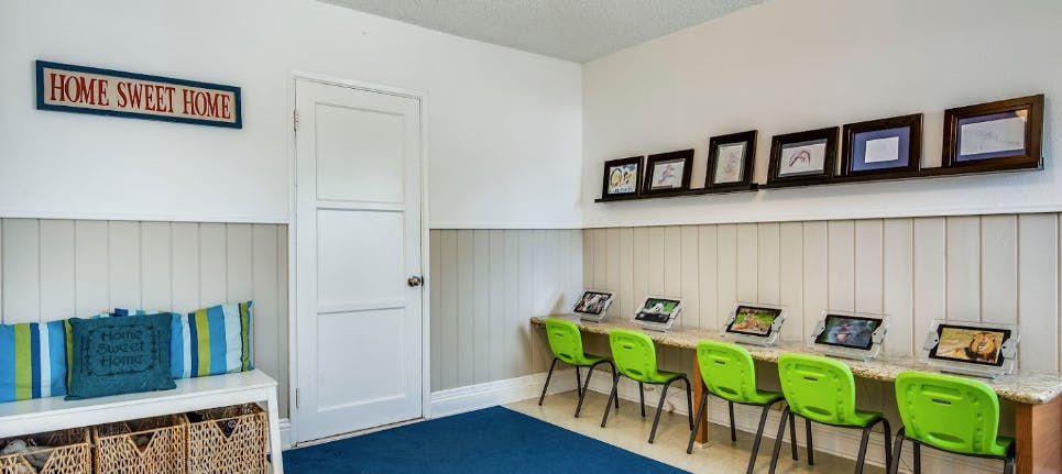 Room with a long desk, green chairs, and tablets