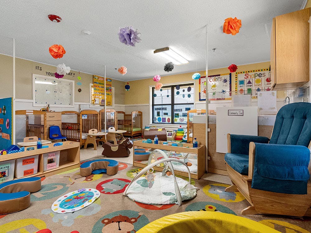 Cribs and play items in a brightly decorated daycare room