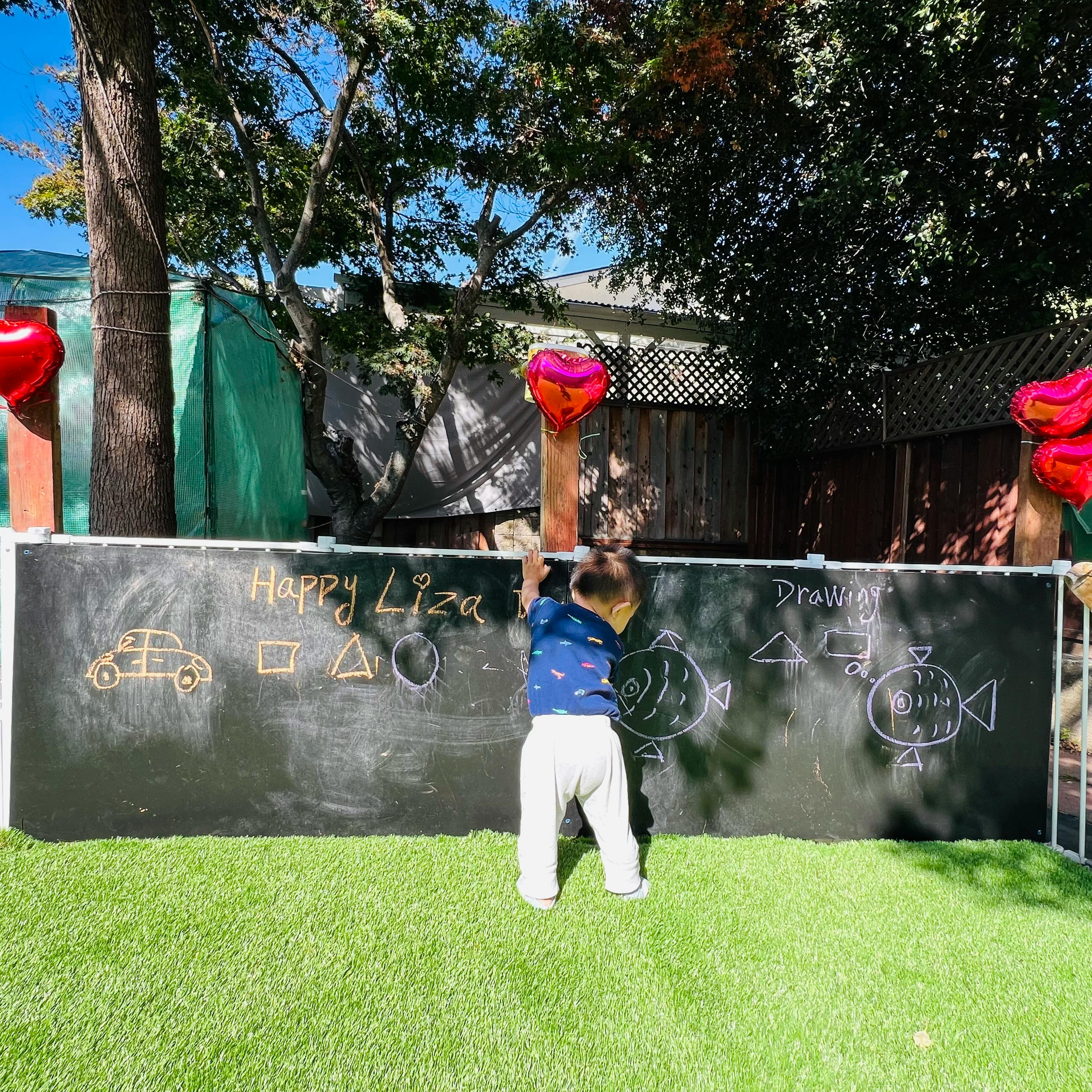 Child drawing with chalk on an outdoor board