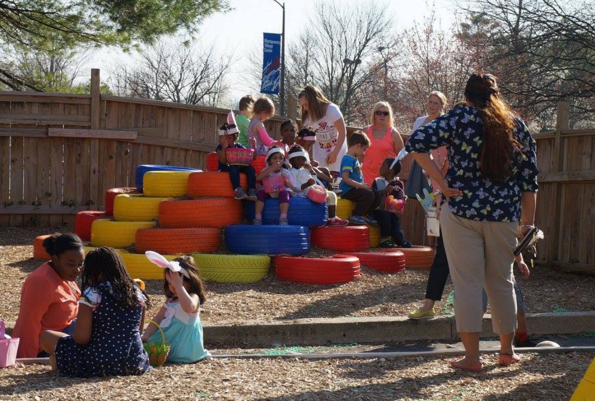 People and children on a playground with colorful tires