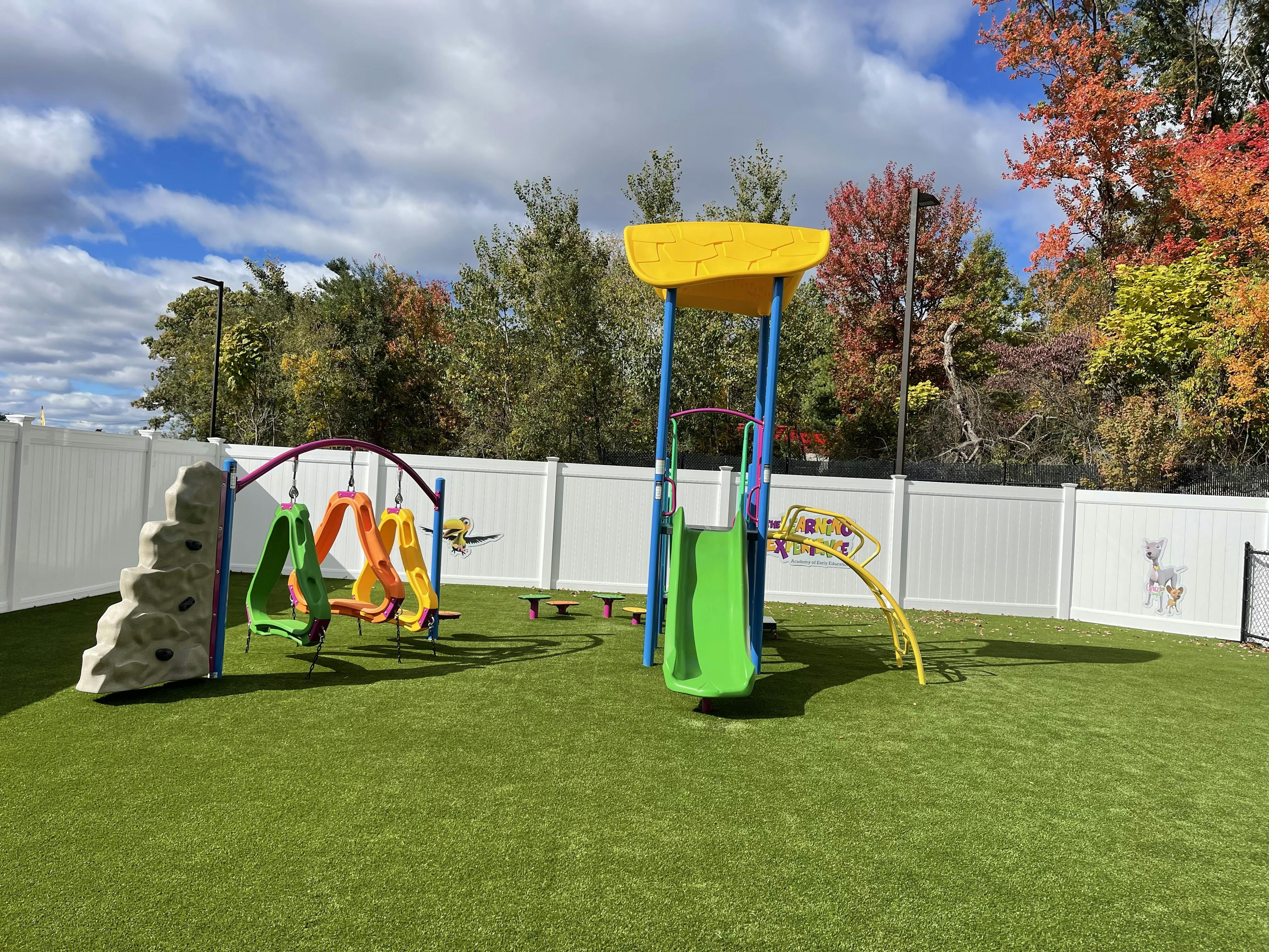 Playground with swings, slide, and climbing wall on artificial turf