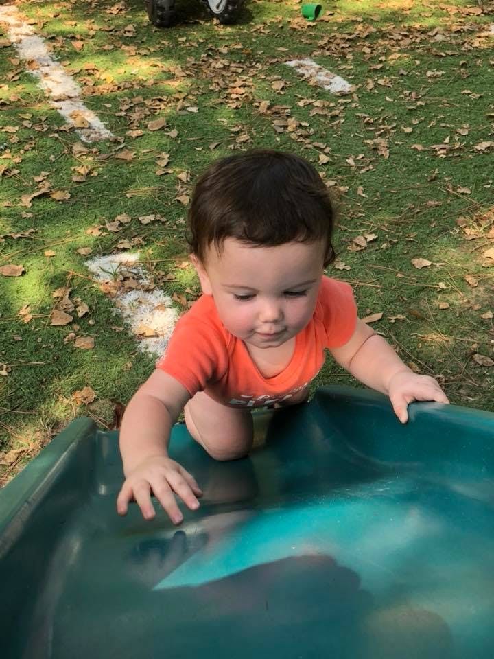 Child on hands and knees at the top of a slide